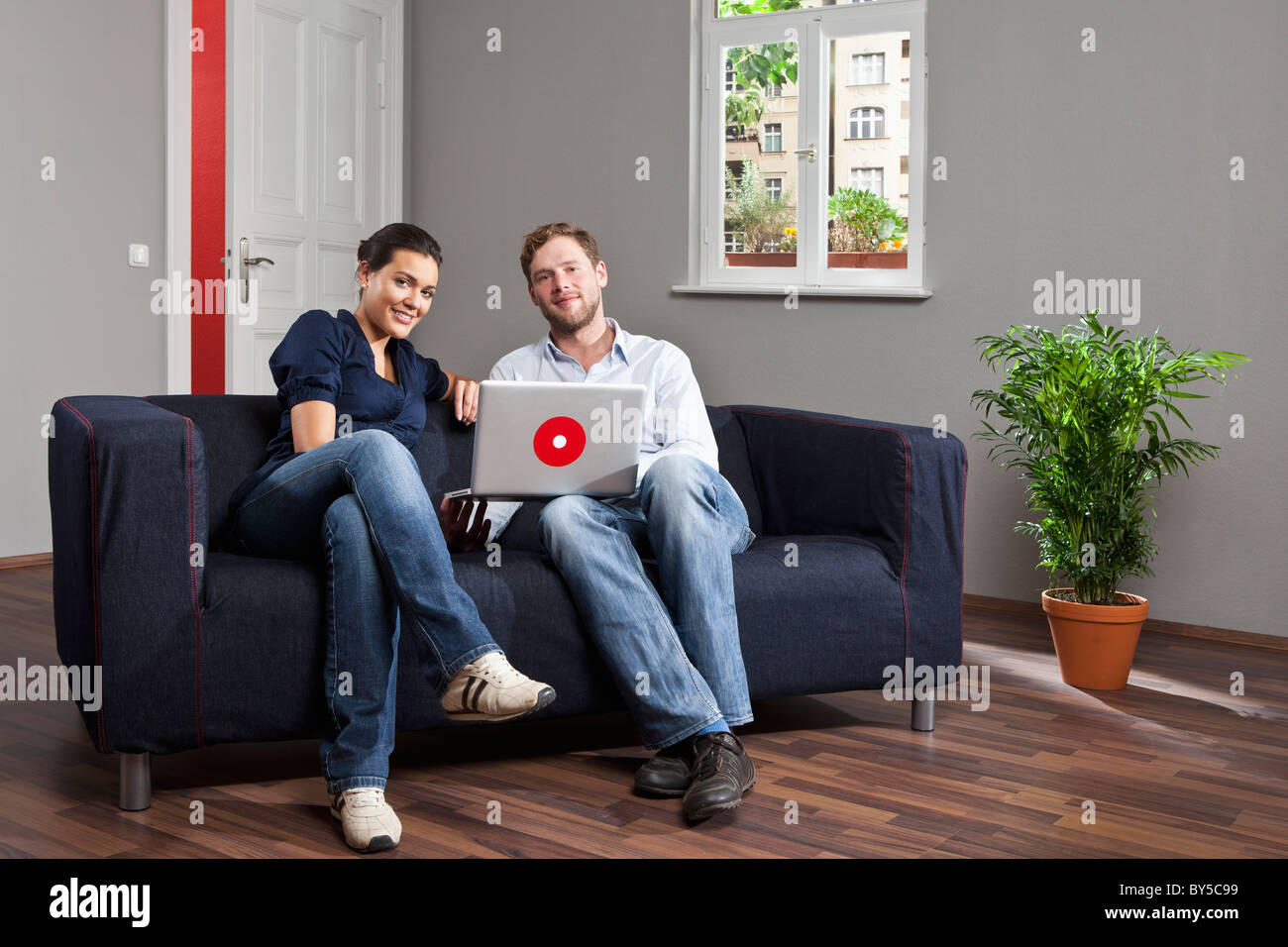 A young couple using a laptop together in their living room Stock Photo ...