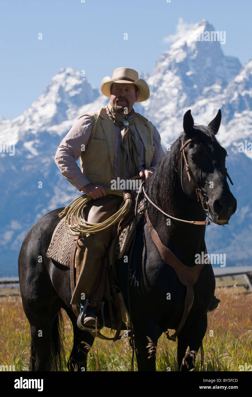 Cowboy on horse with snowy Teton Range in the distance Stock Photo