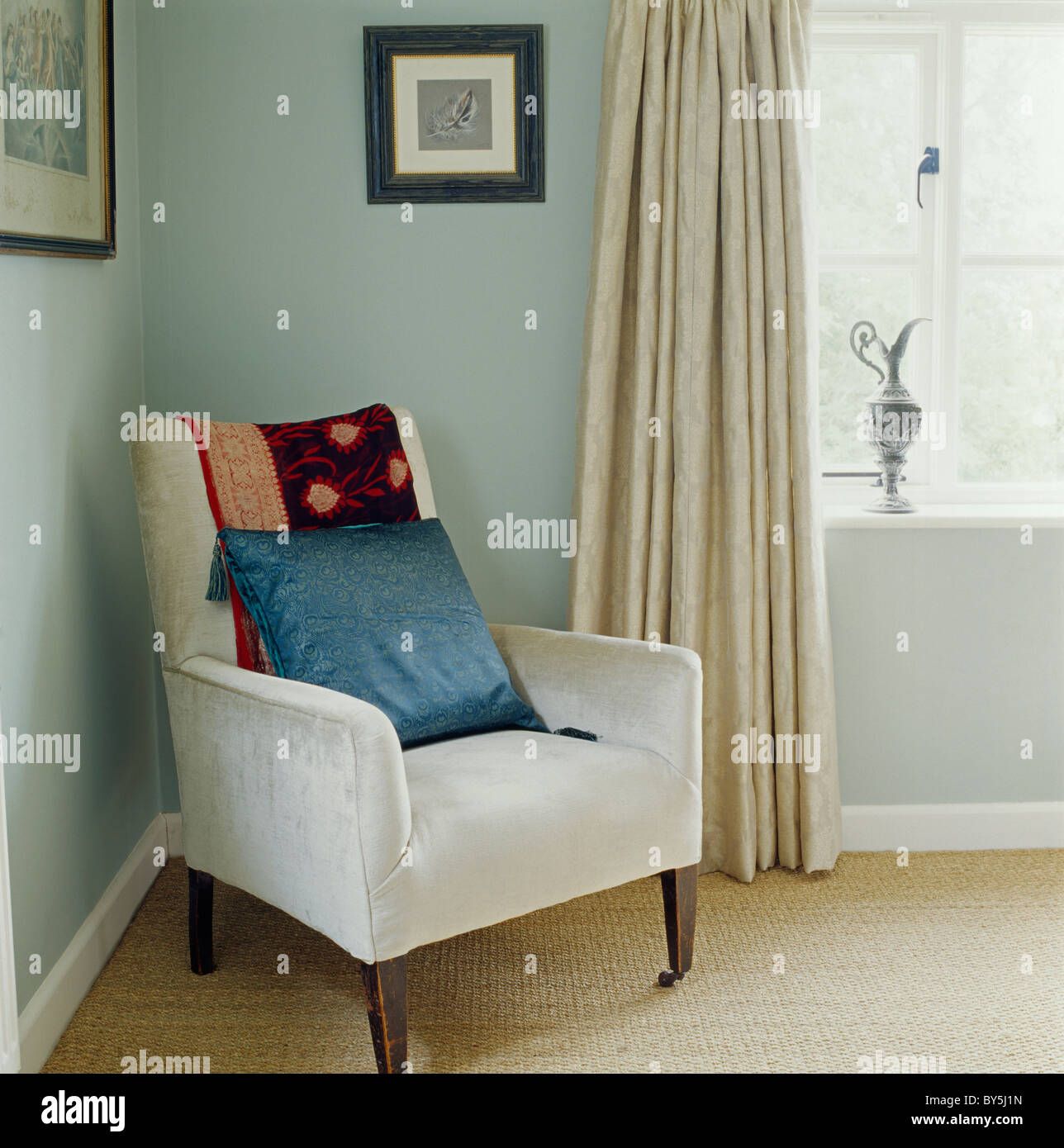 Blue silk cushion on pale gray suede armchair in corner of modern