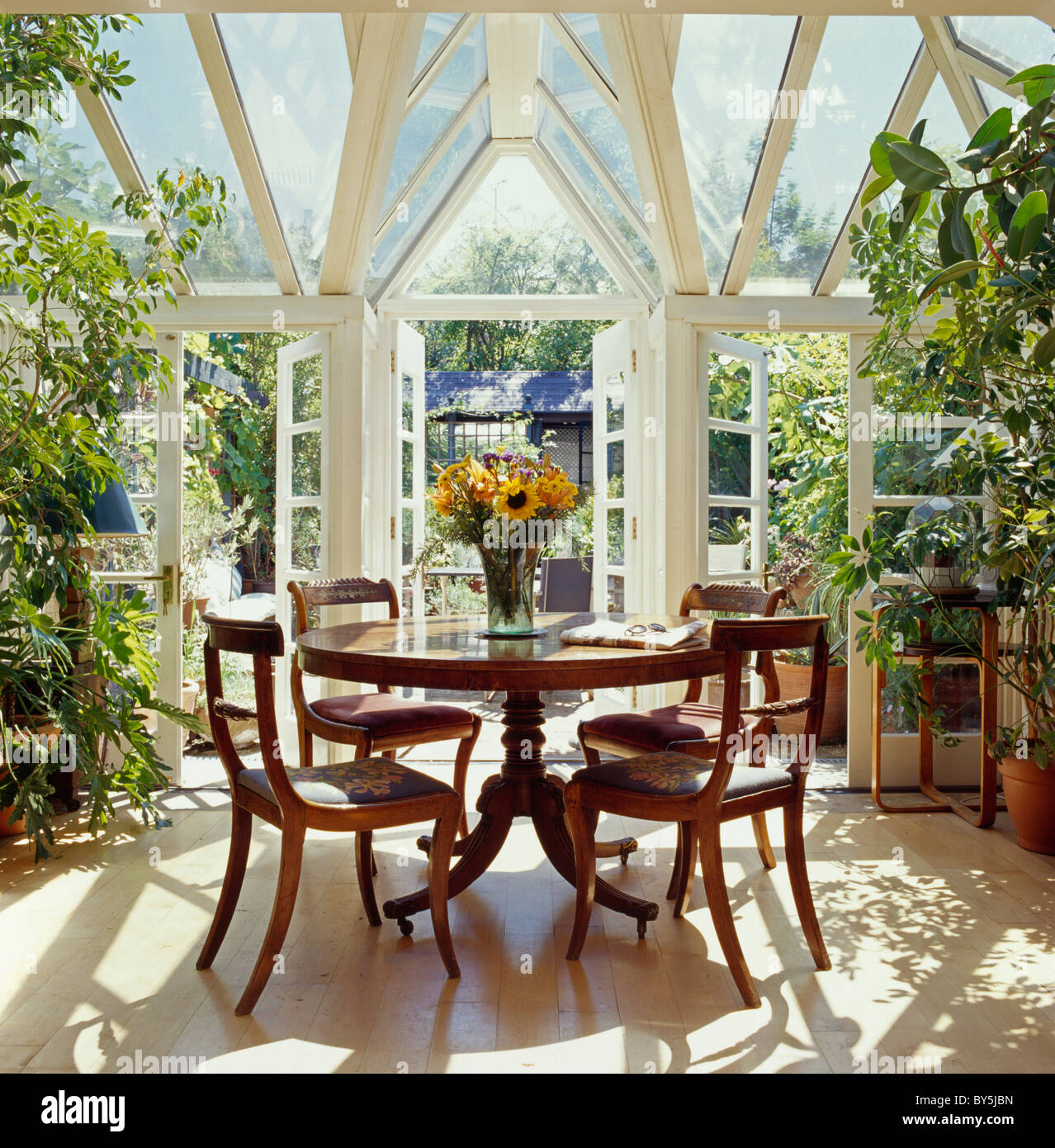 Antique Circular Table And Antique Chairs In Sunny Conservatory