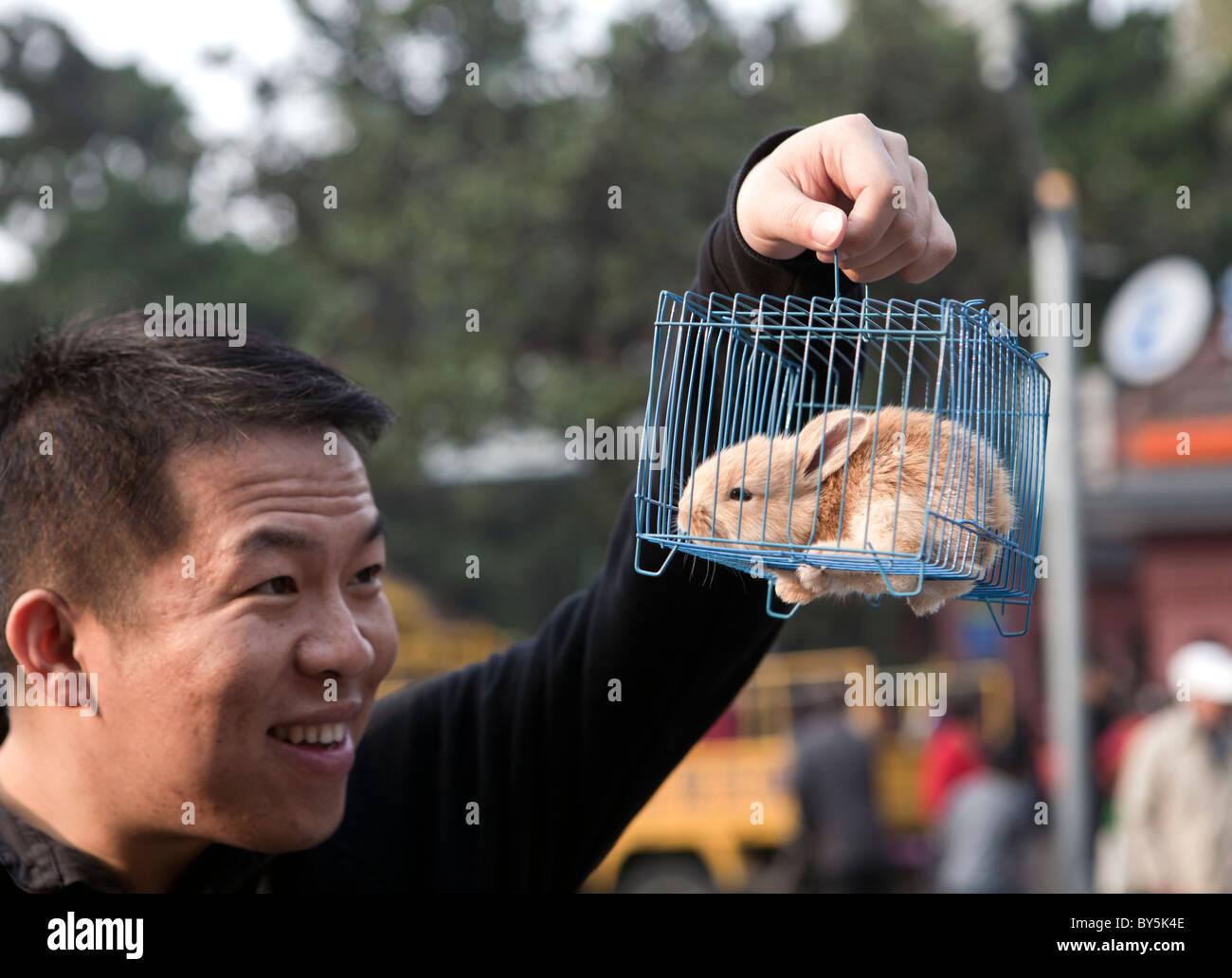 Man holding up caged rabbit in East Jiangwan Road, Shanghai, China ...
