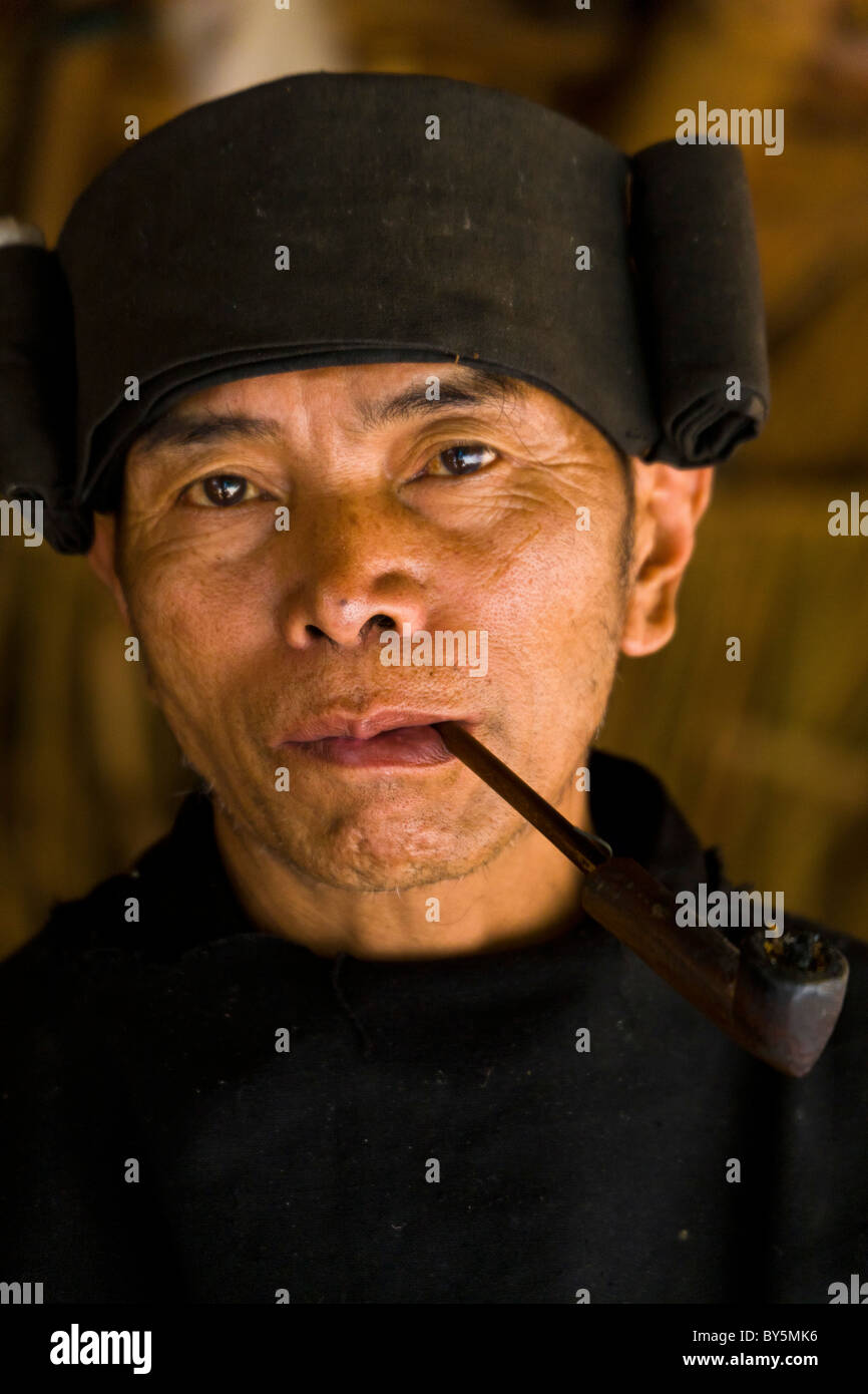 Old Jinuo man smoking pipe, Jinuo Luoke (Jinuo Shan), Jinghong, Xishuangbanna, Yunnan Province, China. JMH4316 Stock Photo