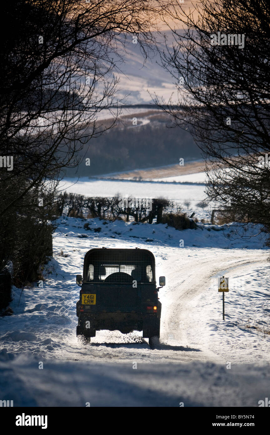 A landrover driving along a snow covered country 'B' road in rural north northumberland. Stock Photo