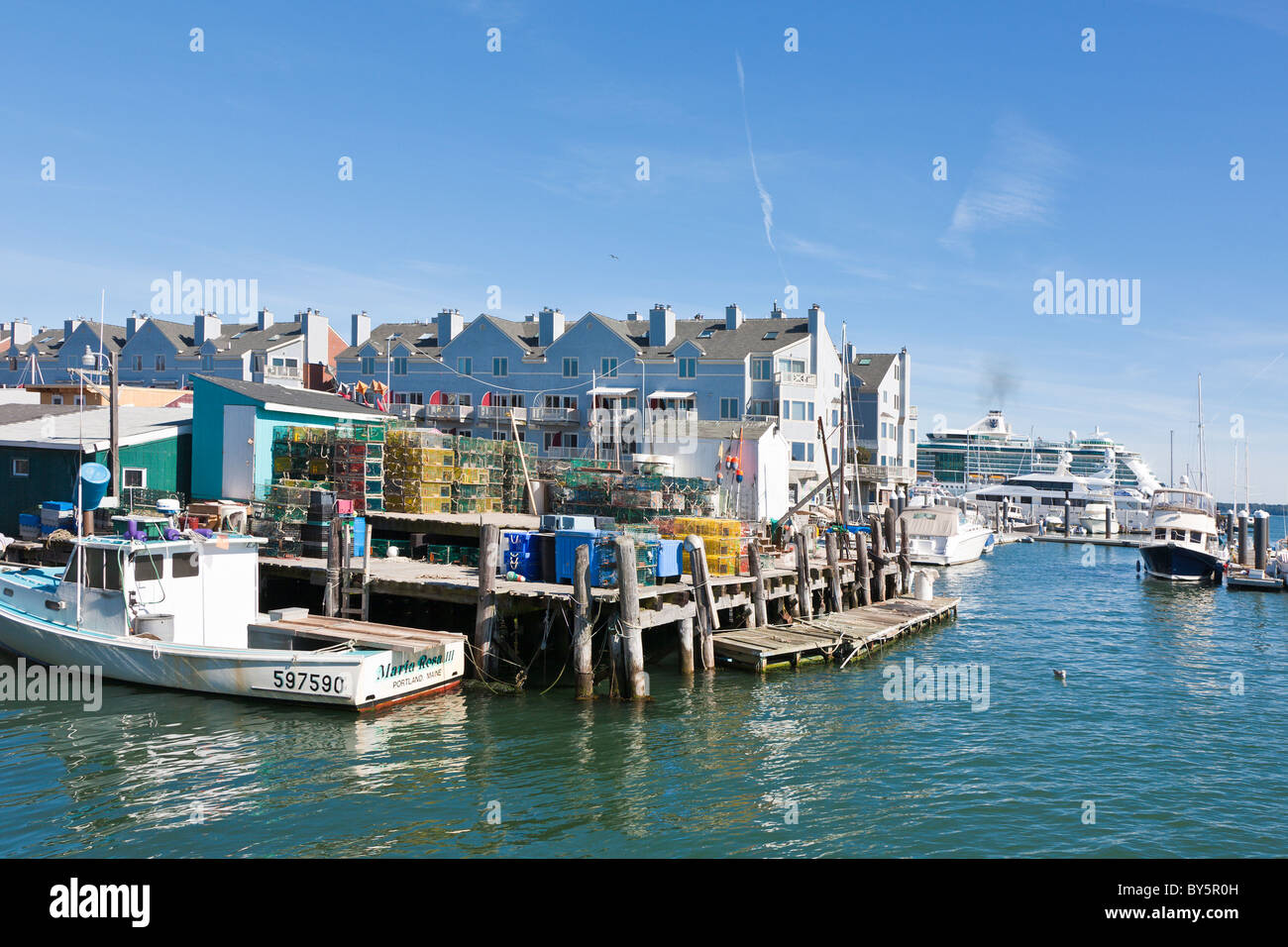 Commercial fishing boat and stacks of lobster traps on the end of Widgery Wharf in Portland, Maine Stock Photo