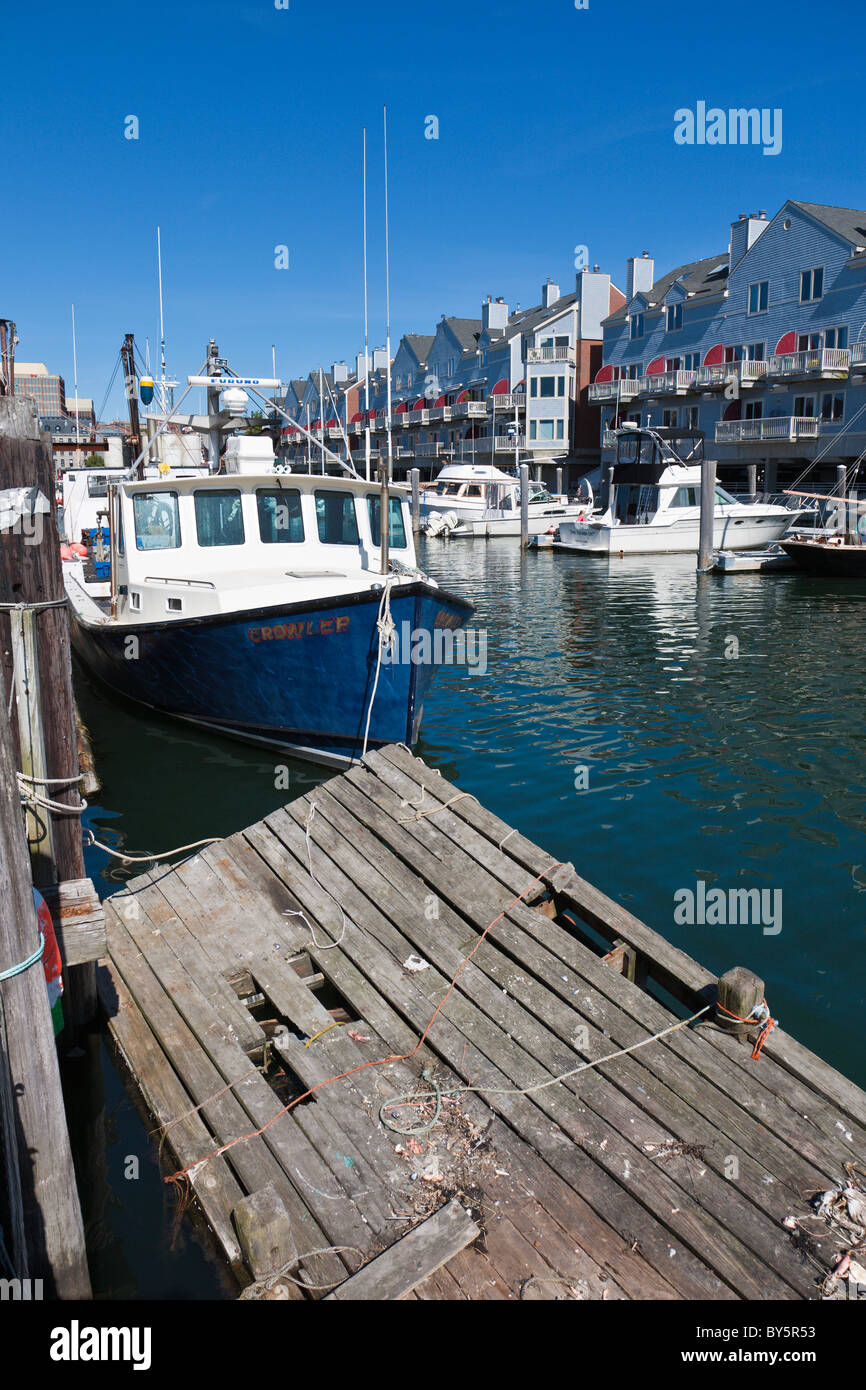 Private and commercial fishing boats docked at wharf near apartments