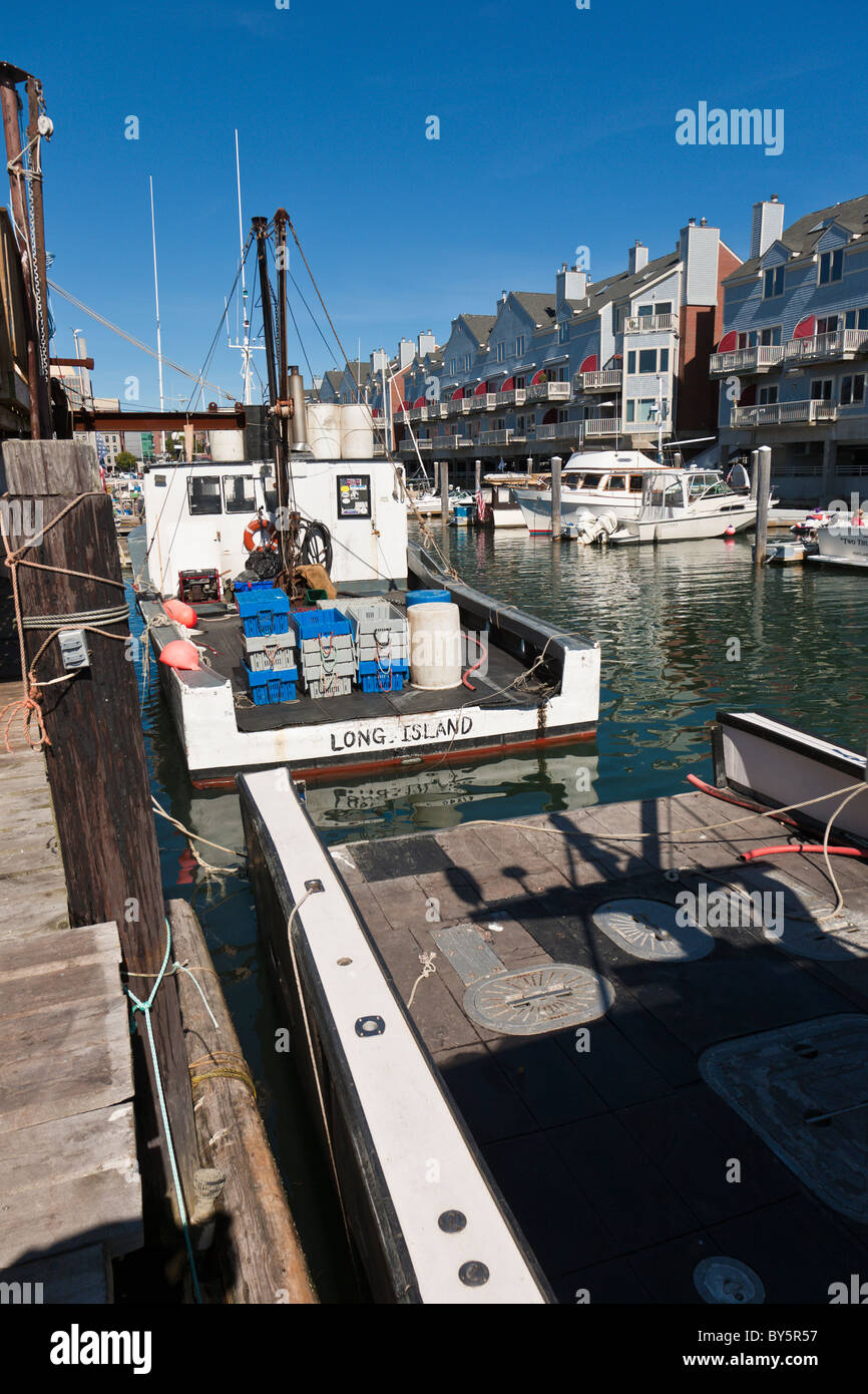 Private and commercial fishing boats docked at wharf near apartments