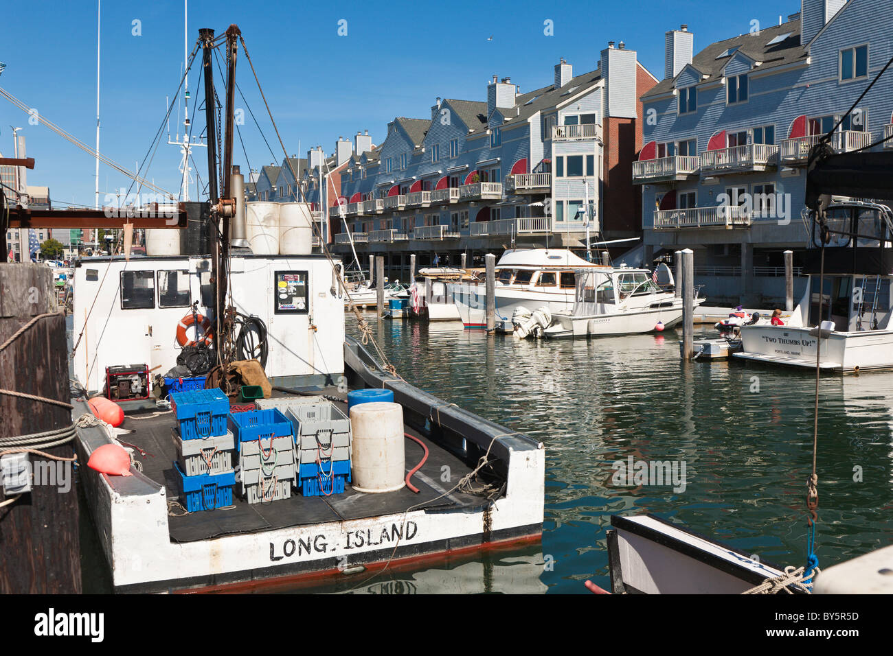 Private and commercial fishing boats docked at wharf near apartments