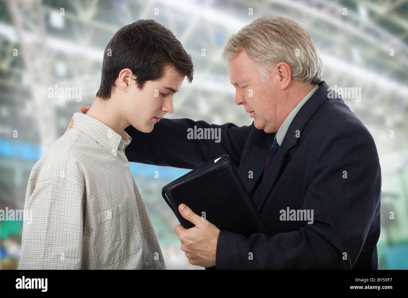 Preacher leading a young man in prayer to receive Lord Jesus Stock Photo