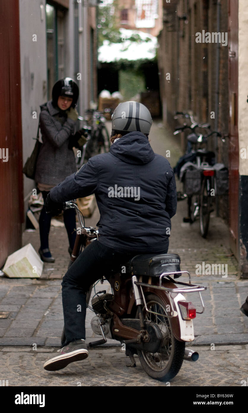 Young man on Moped about to pick up a young lady in Bruges, Belgium. Stock Photo