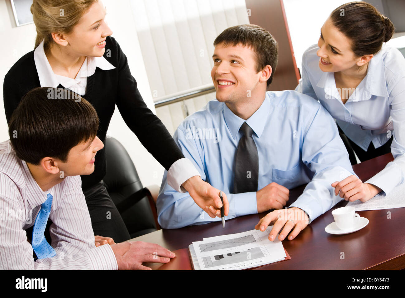 Four smiling business people discussing an affair Stock Photo - Alamy