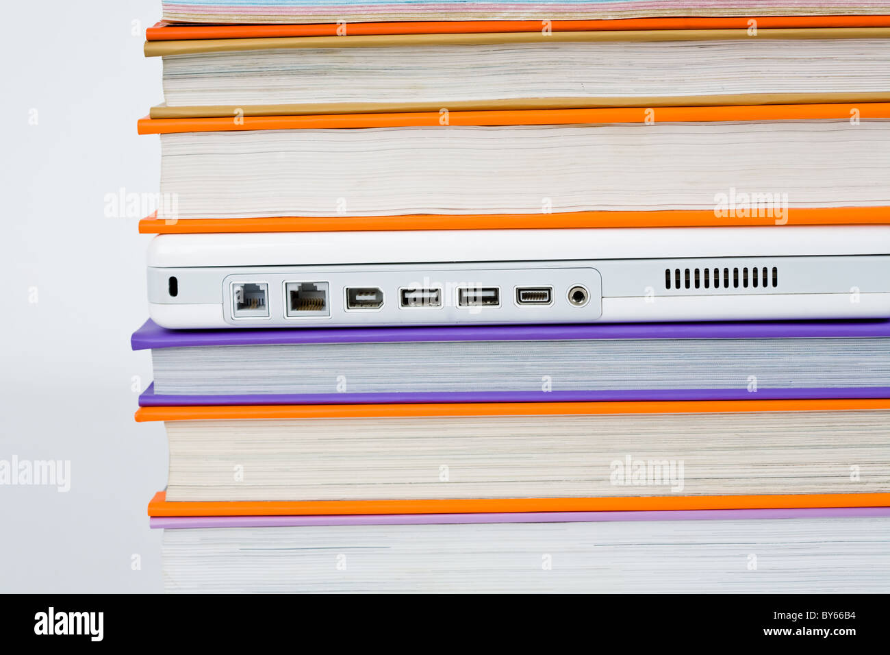 Computer Between Books Horizontal image of white laptop between colorful books Stock Photo - Alamy