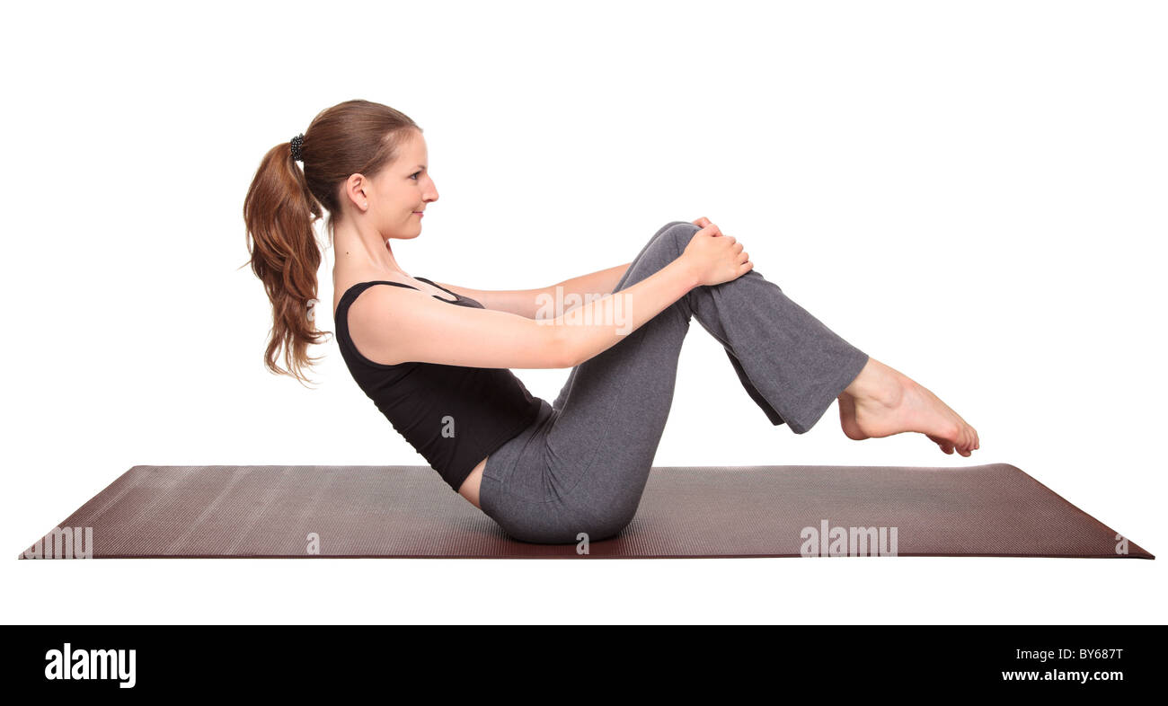 Isolated studio shot of a fit Caucasian woman doing a spinal rocking exercise. Stock Photo