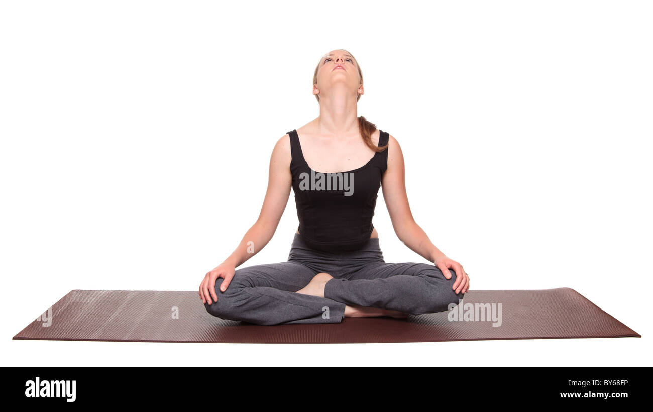 Isolated studio shot of a fit Caucasian woman sitting on an exercise mat and stretching her neck. Stock Photo