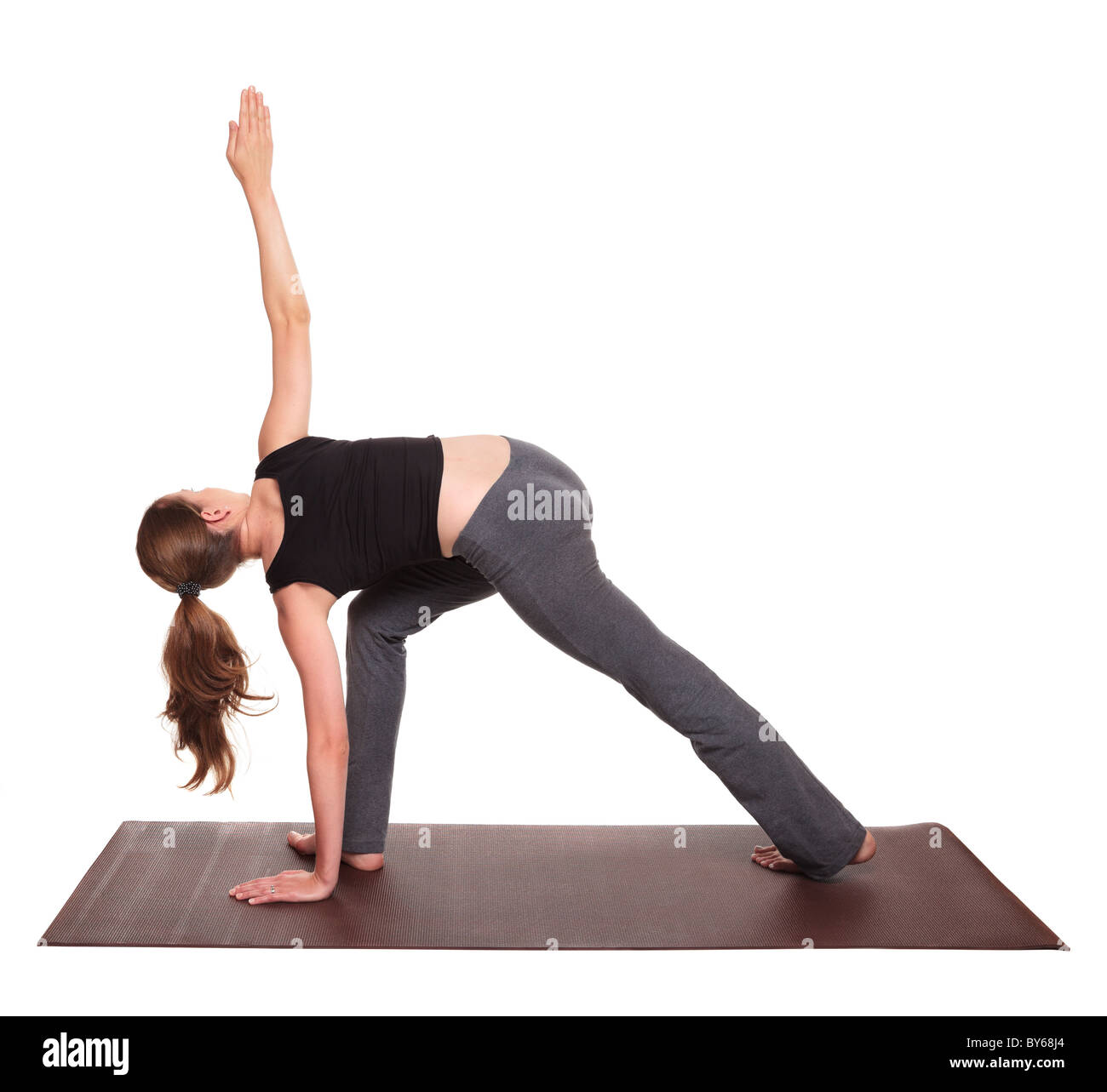 Isolated studio shot of a fit Caucasian woman holding the parivrtta parsvakonasana Side Angle Twist yoga position on an exercise Stock Photo