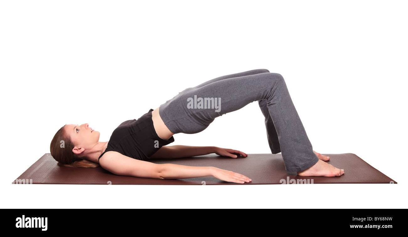 Isolated studio shot of a fit Caucasian woman holding the Bridge Pose (setu bhandasana) yoga position on an exercise mat. Stock Photo