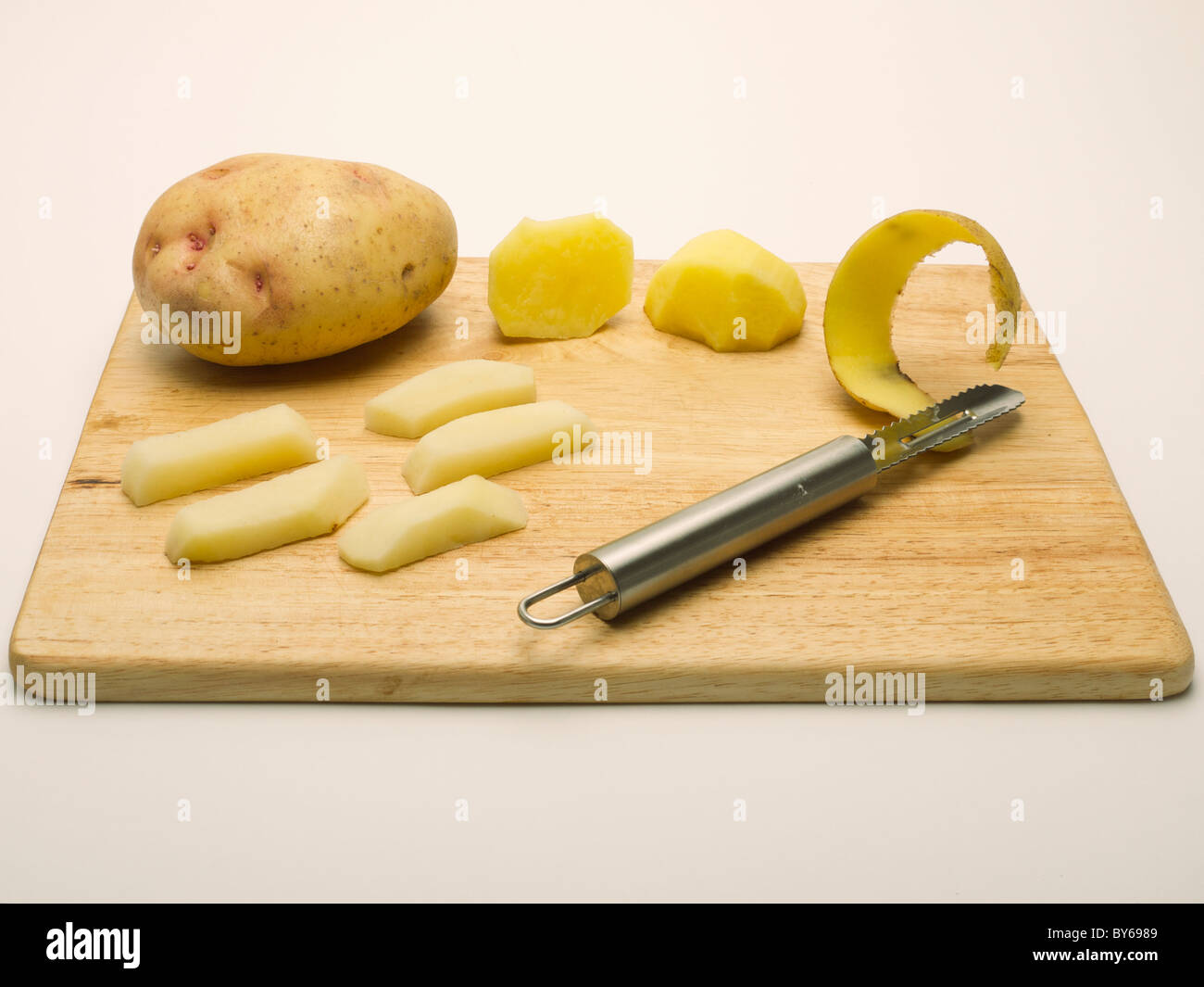 Different raw potatoes on a cutting board. Whole potato, sliced potato