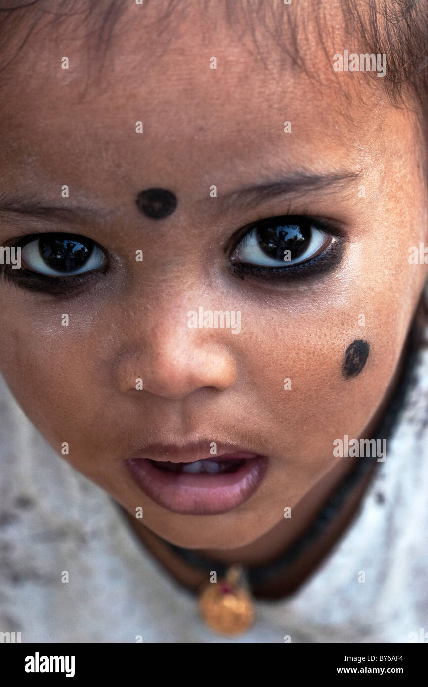 Small Indian child with kohl applied in spots to ward off 'the evil eye', South India. Kohl is an ancient eye cosmetic. Stock Photo