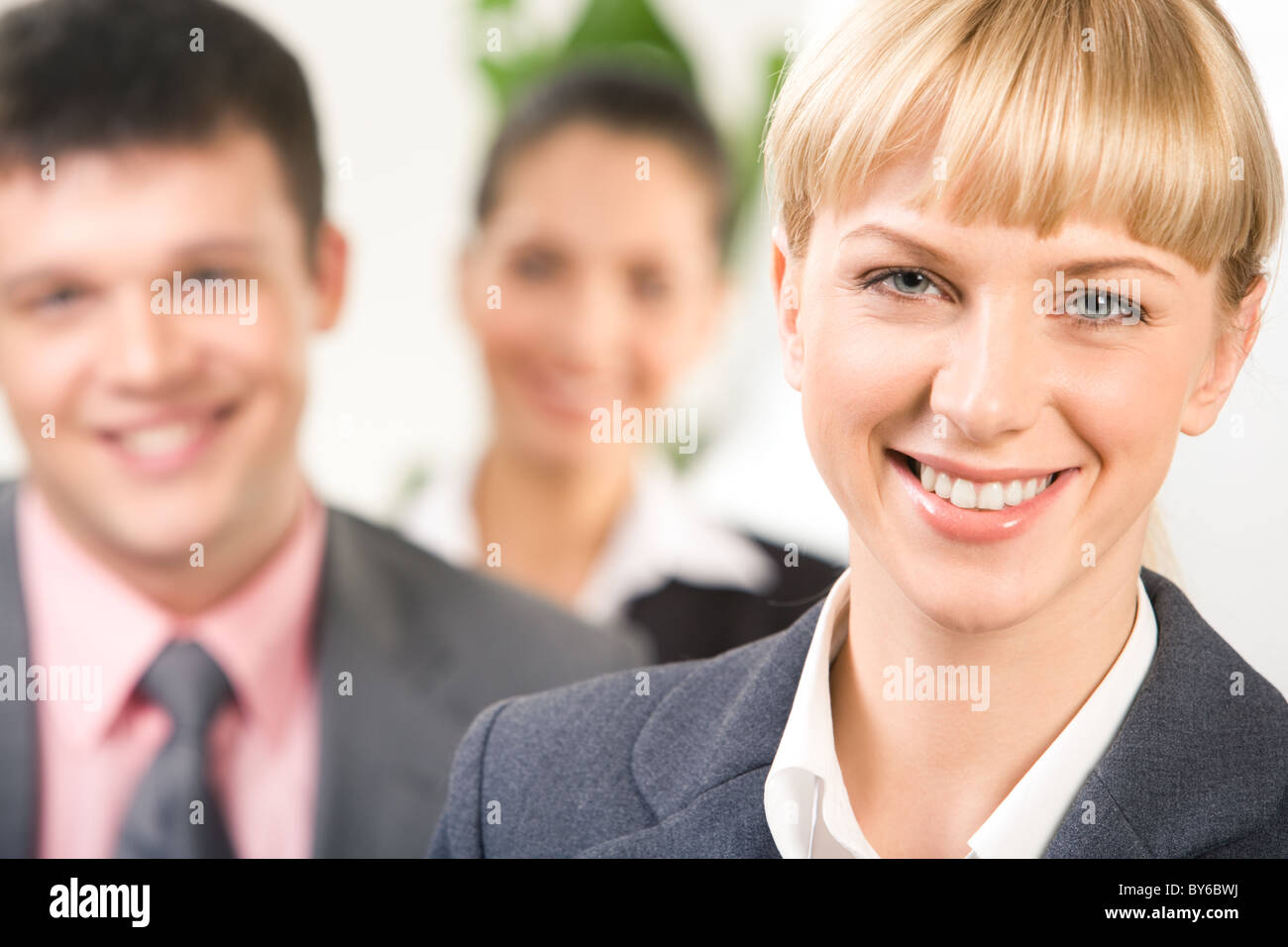 Close-up of blonde woman looking at camera with her business partners