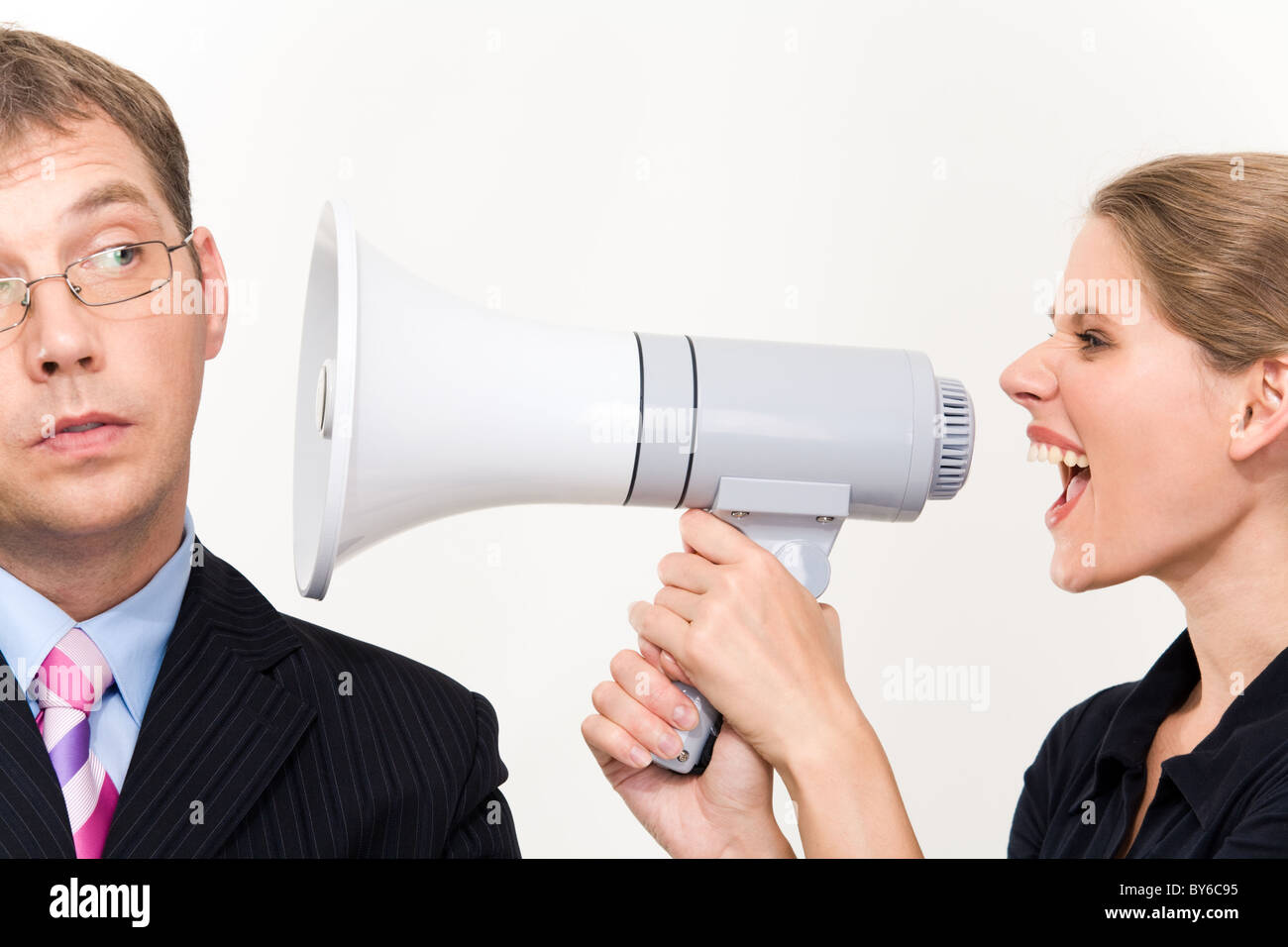 Close-up of young furious woman screaming at her boss through megaphone Stock Photo