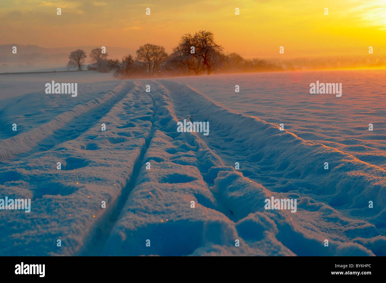 Sunrise with snow at Maulbronn, morning mood, fog with snow, dirt road with snow, sun with rays, snow, landscape Stock Photo