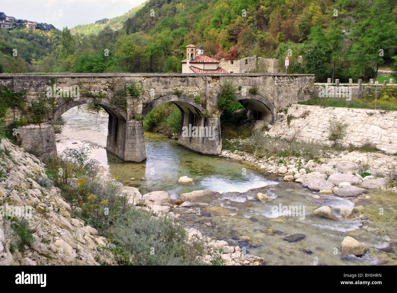 mountain river with a bridge and church in the background Stock Photo