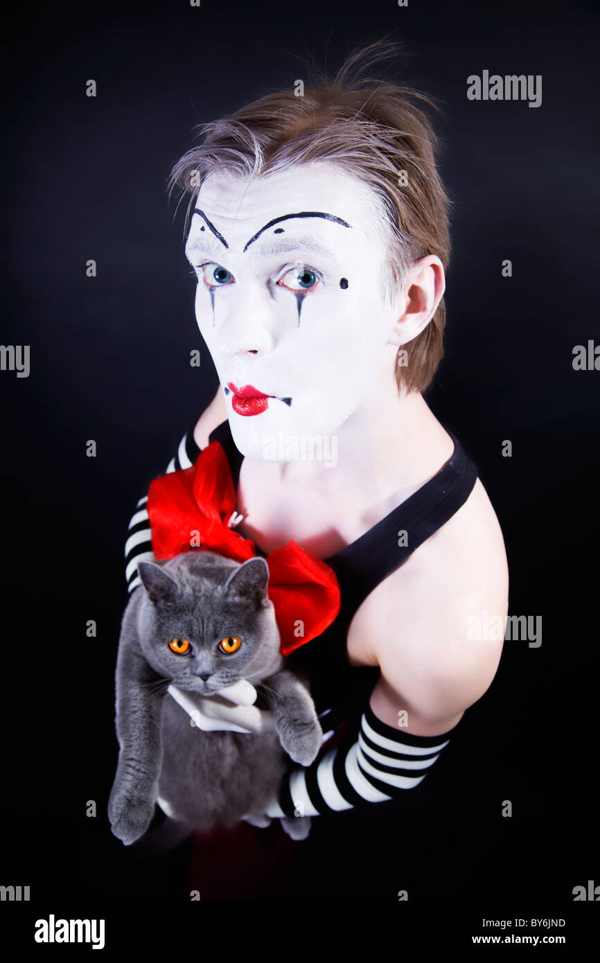 Theatrical mime with red bow and gray British cat in hands Stock Photo