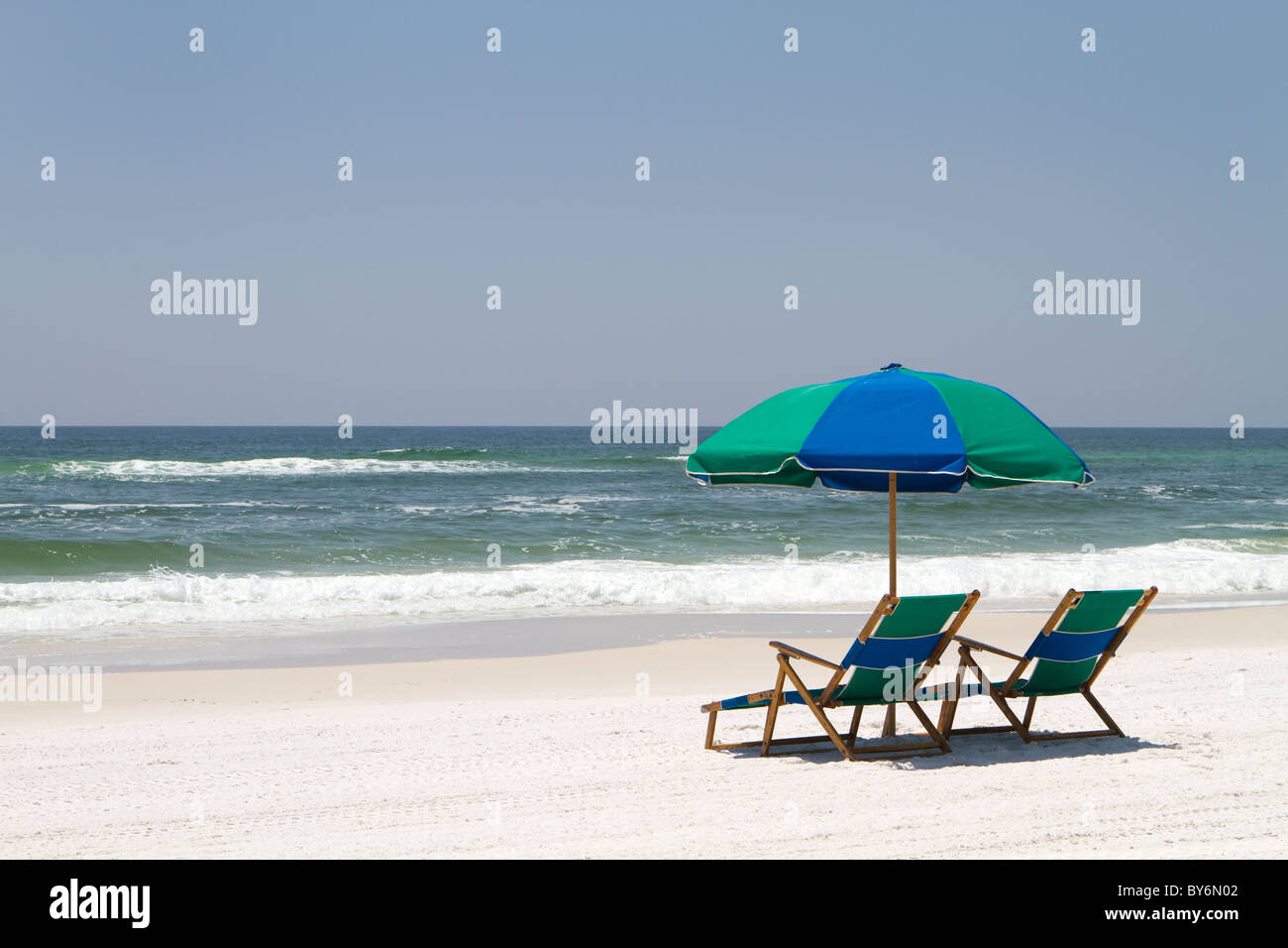 Two beach chairs and an umbrella sit on the sand at Fort Walton Beach, Florida. Stock Photo