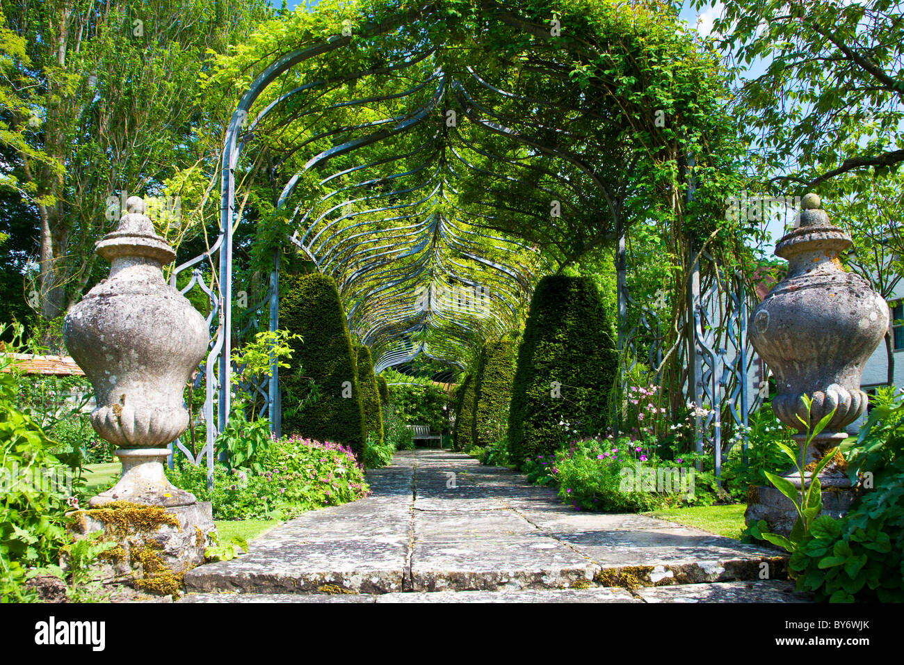 A shady path under a pergola in an English country garden in summer. Stock Photo