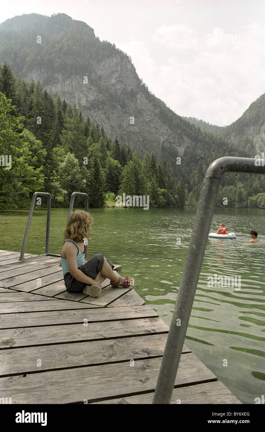 Young girl sitting on a wooden platform on lake Gleinkersee, Windischgarsten, Austria, Alps, Europe Stock Photo