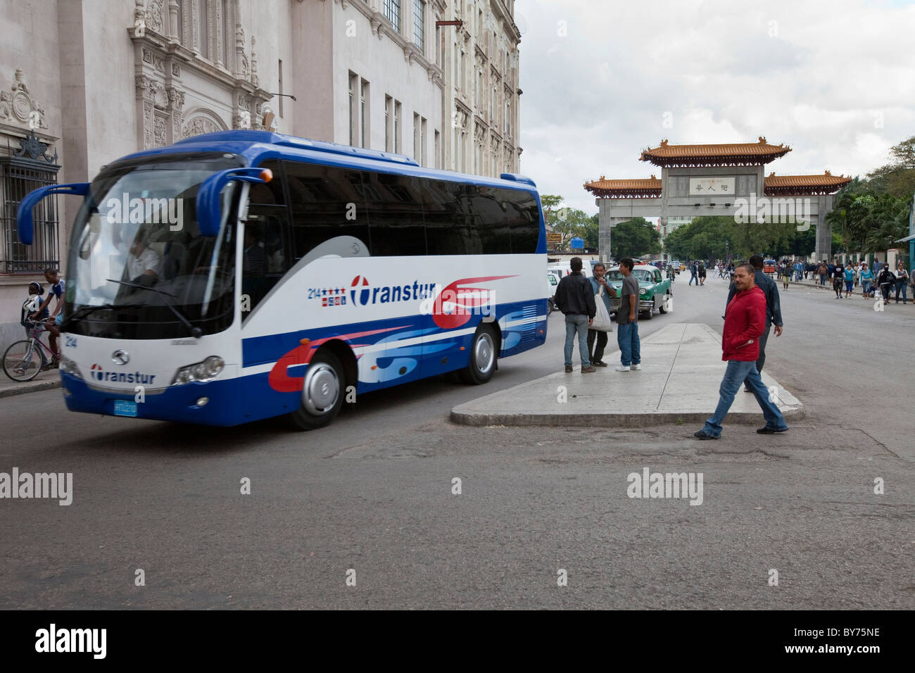 Cuba, Havana. Modern Tour Buses Serve Cuba's Tourism Industry. Gate Marking Exit From China Town in Background. Stock Photo