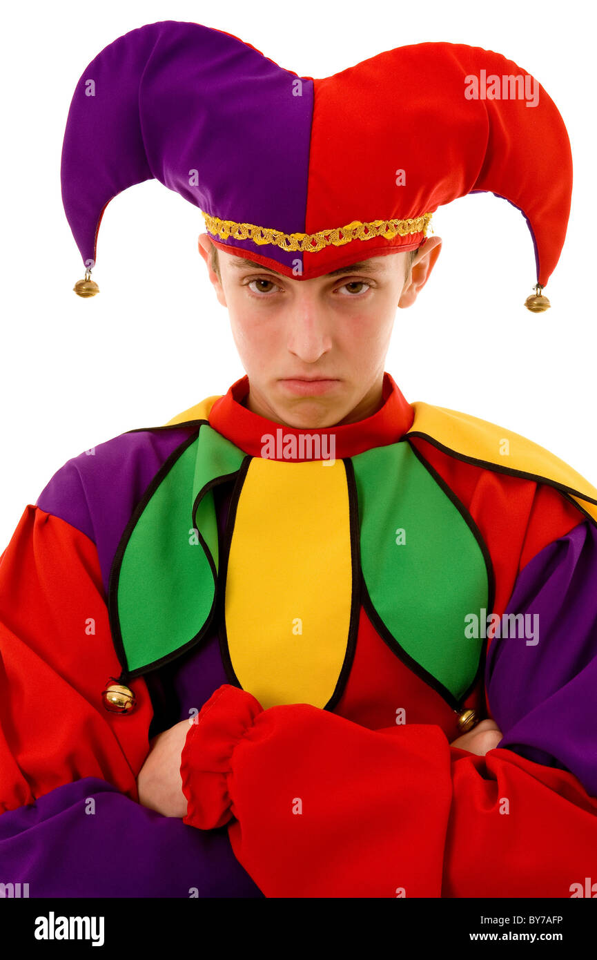 Head and shoulders studio shot of a caucasian male Jester, looking miserable with arms folded in a defensive stance.  White background Stock Photo