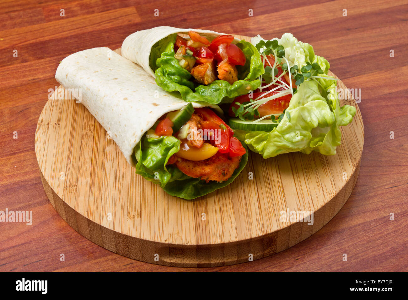 Spicy chicken with salad and salsa wrapped in a soft flour tortilla. Stock Photo