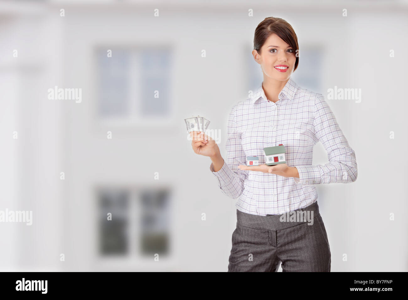 Young beautiful business woman with house model and dollars in hands ...