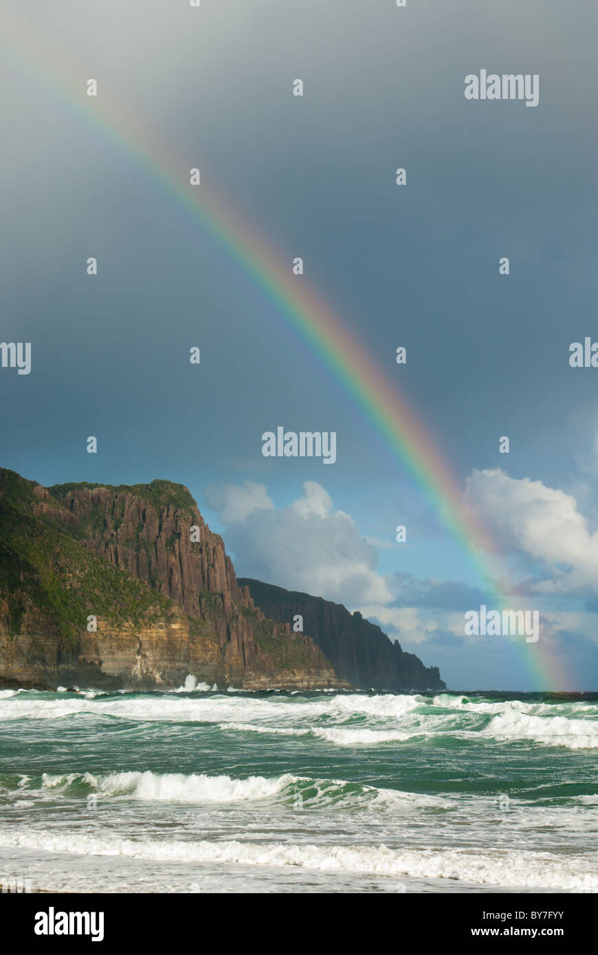 Rainbow after hailstorm over coastal cliffs Stock Photo
