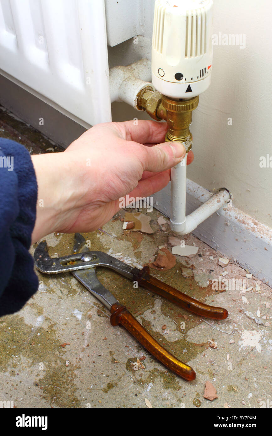 DIY plumber repairing a leaky radiator pipe, UK Stock Photo