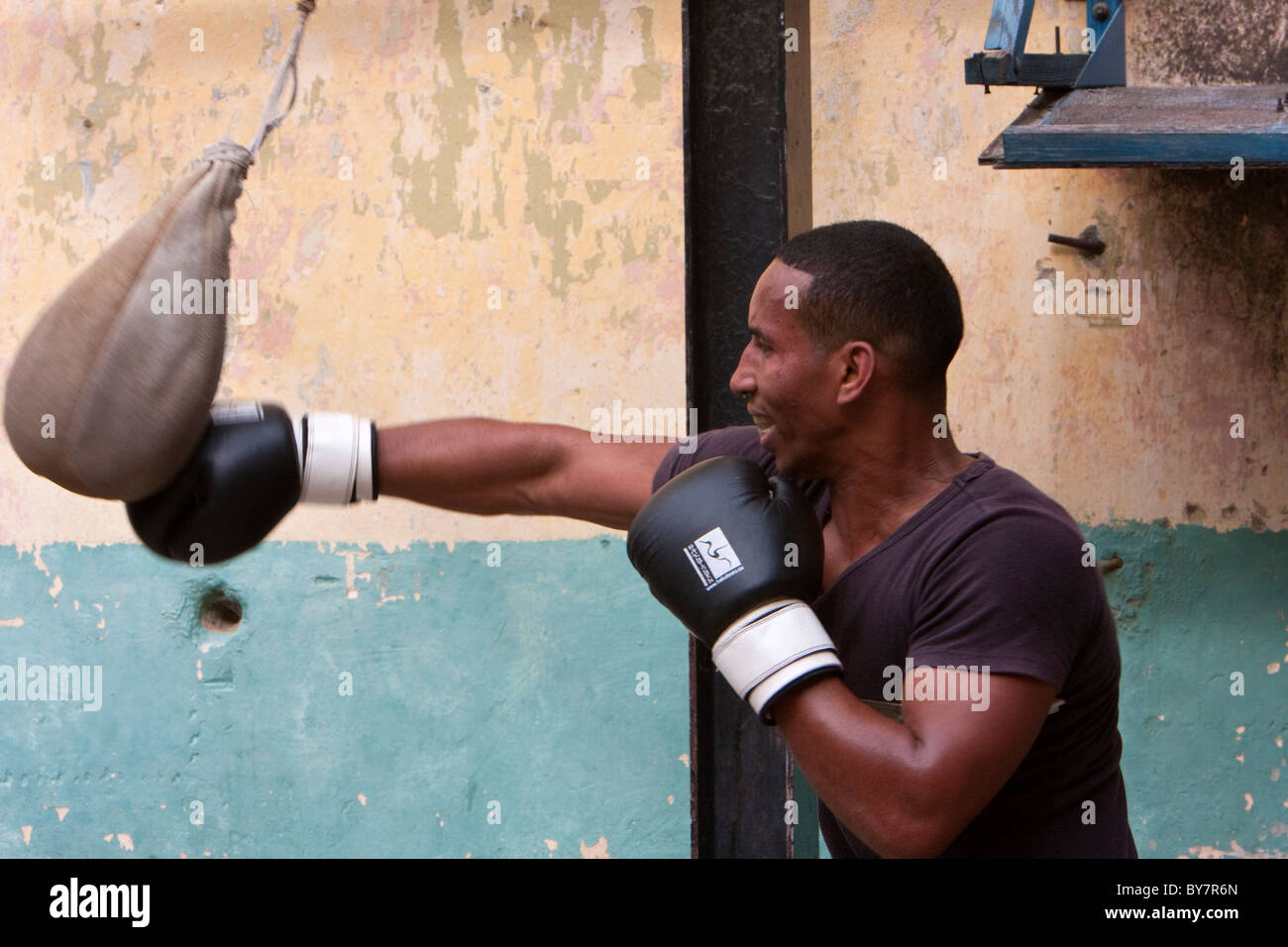 Cuba, Havana. Afro-Cuban Boxer Practicing with a Punching Bag. Stock Photo