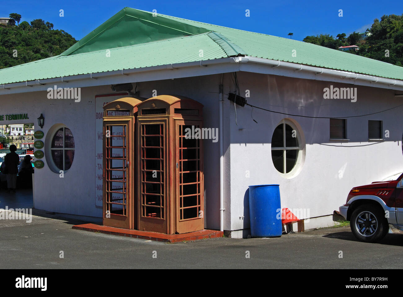 Two old and faded English red telephone boxes outside building, St. George's, Grenada, Caribbean. Stock Photo
