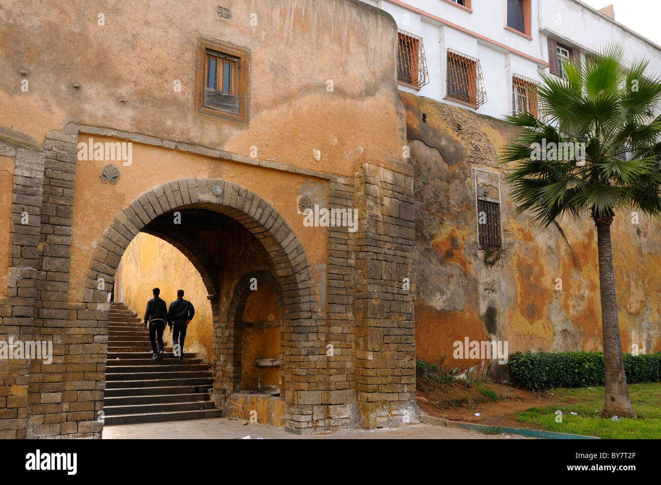 Two young men walking up the steps of the East entrance gate to the Old Medina Casablanca Morocco North Africa Stock Photo