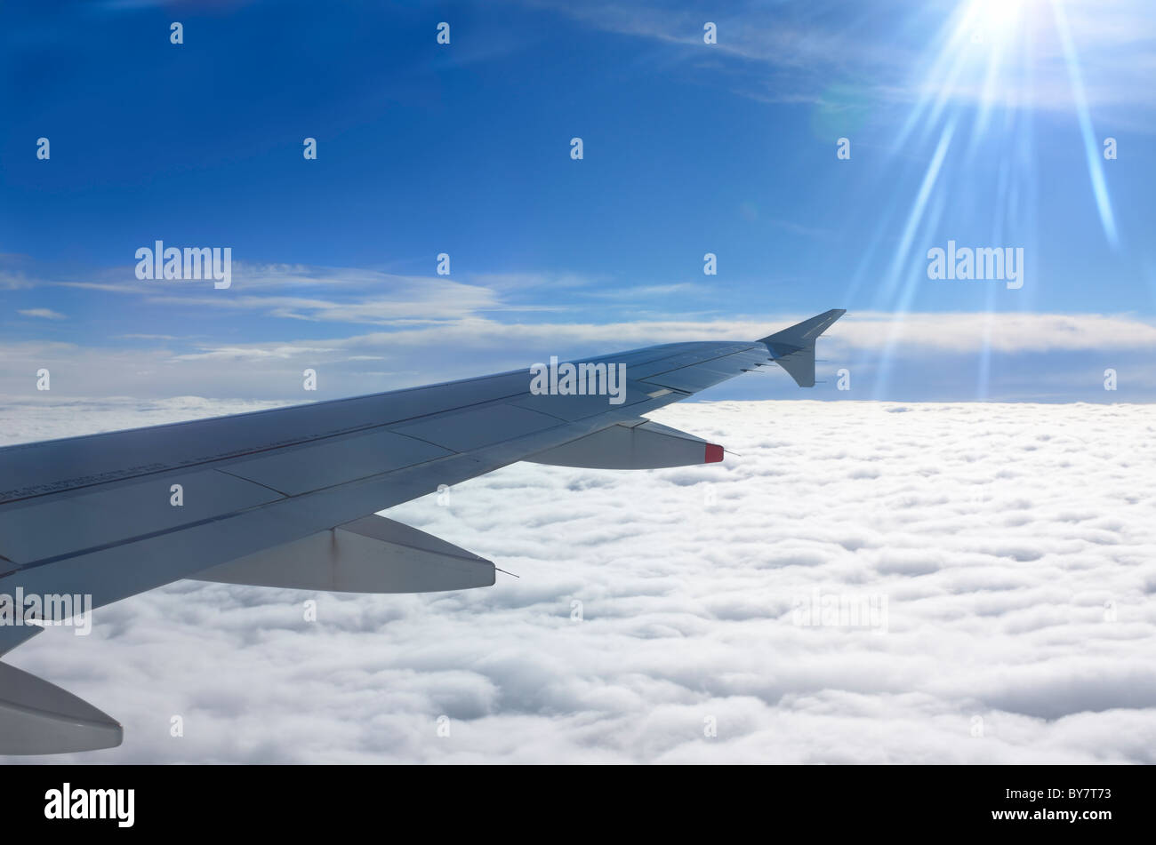 Flying above the clouds with jet aircraft wing and sun flare Stock ...