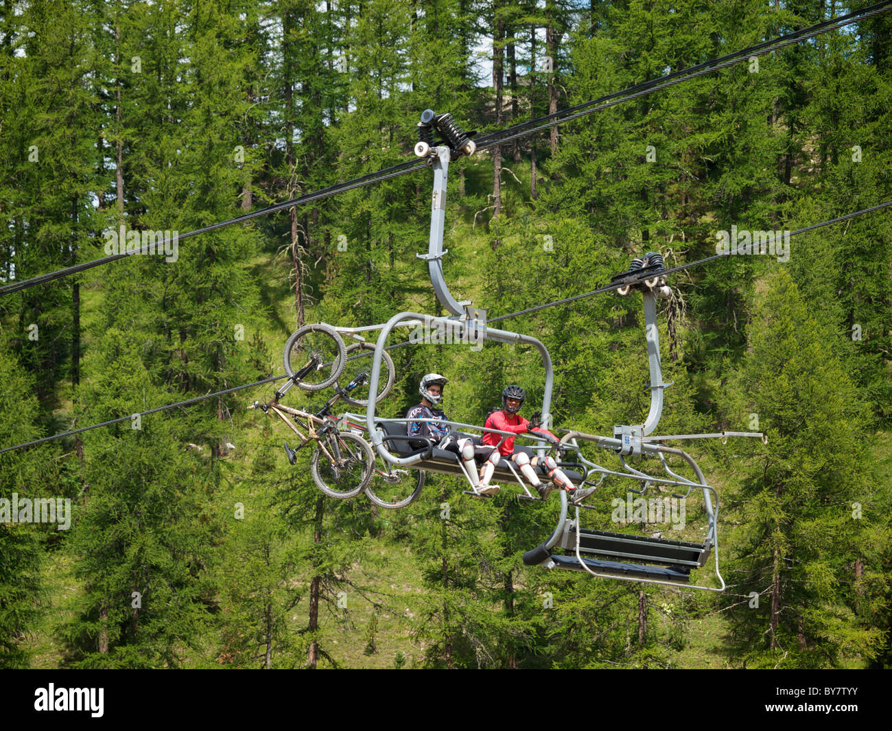 Mountainbikers going up the slope using the ski lift, Les Orres, Hautes Alpes, France Stock Photo
