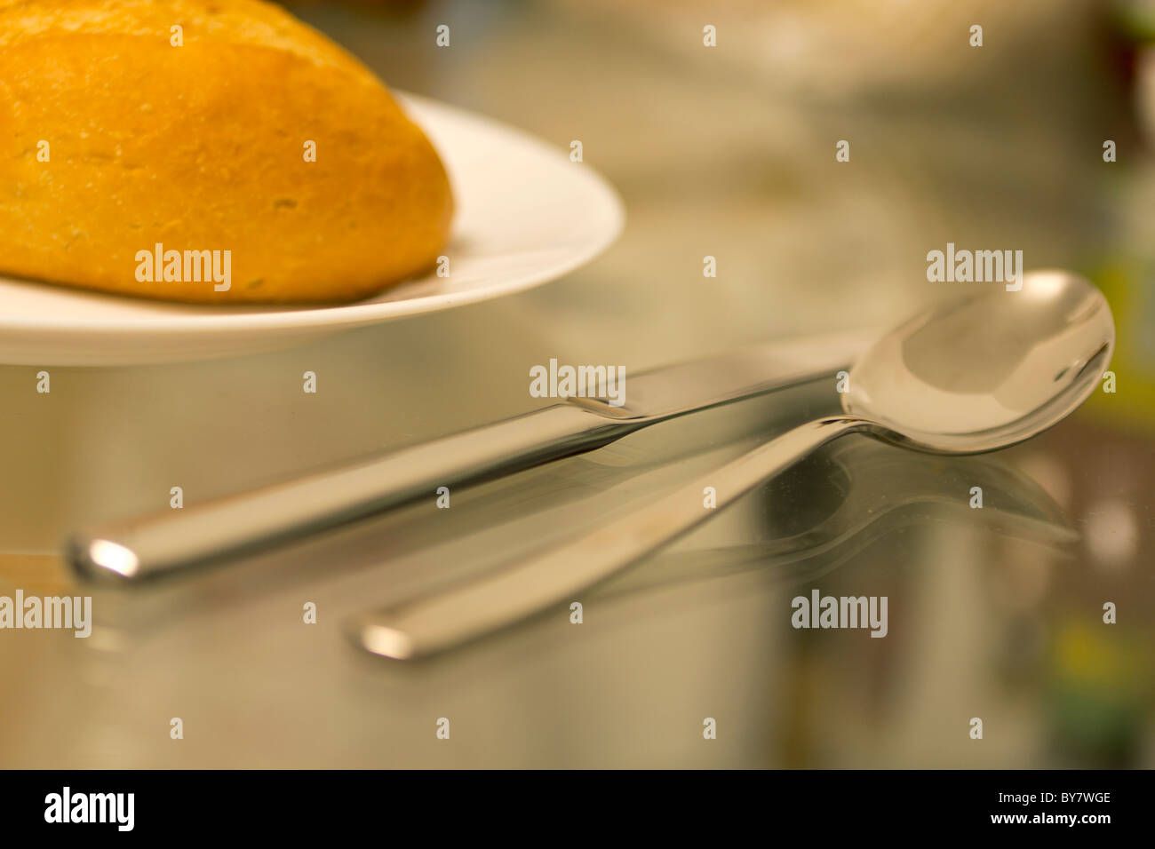Breakfast: Bread, knive and spoon lying on the kitchen table (glass) Stock Photo