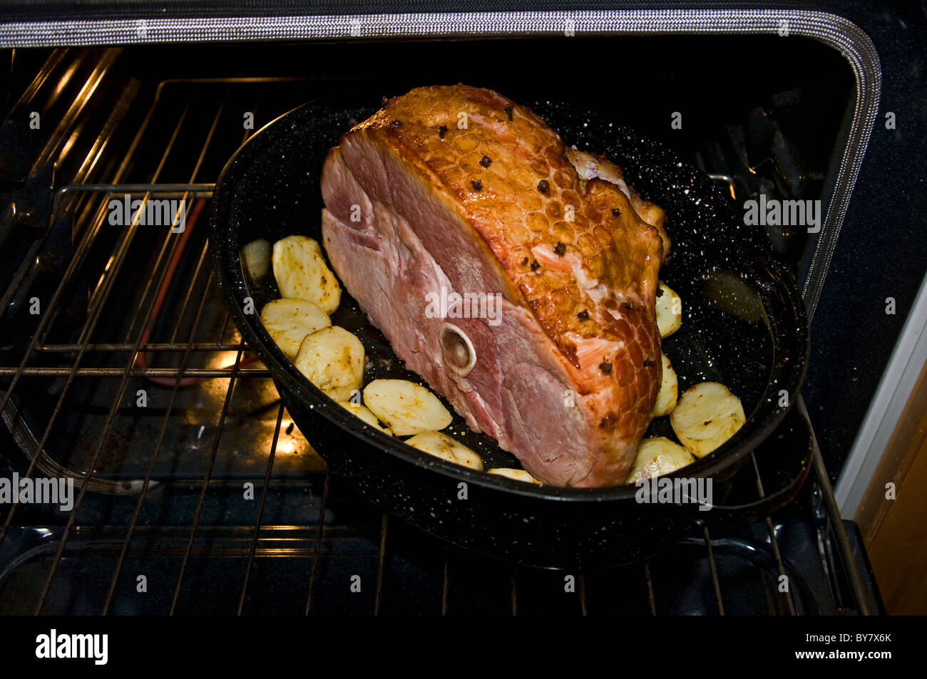 Cooked Smoked ham with cloves and roasted potatoes coming out of the