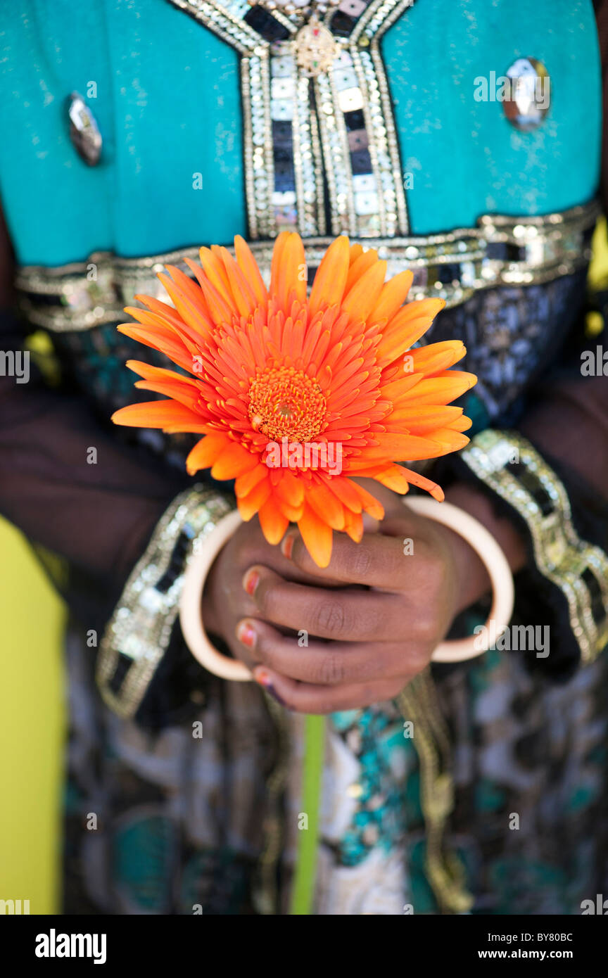 Young indian girl holding an orange gerbera flower. India Stock Photo