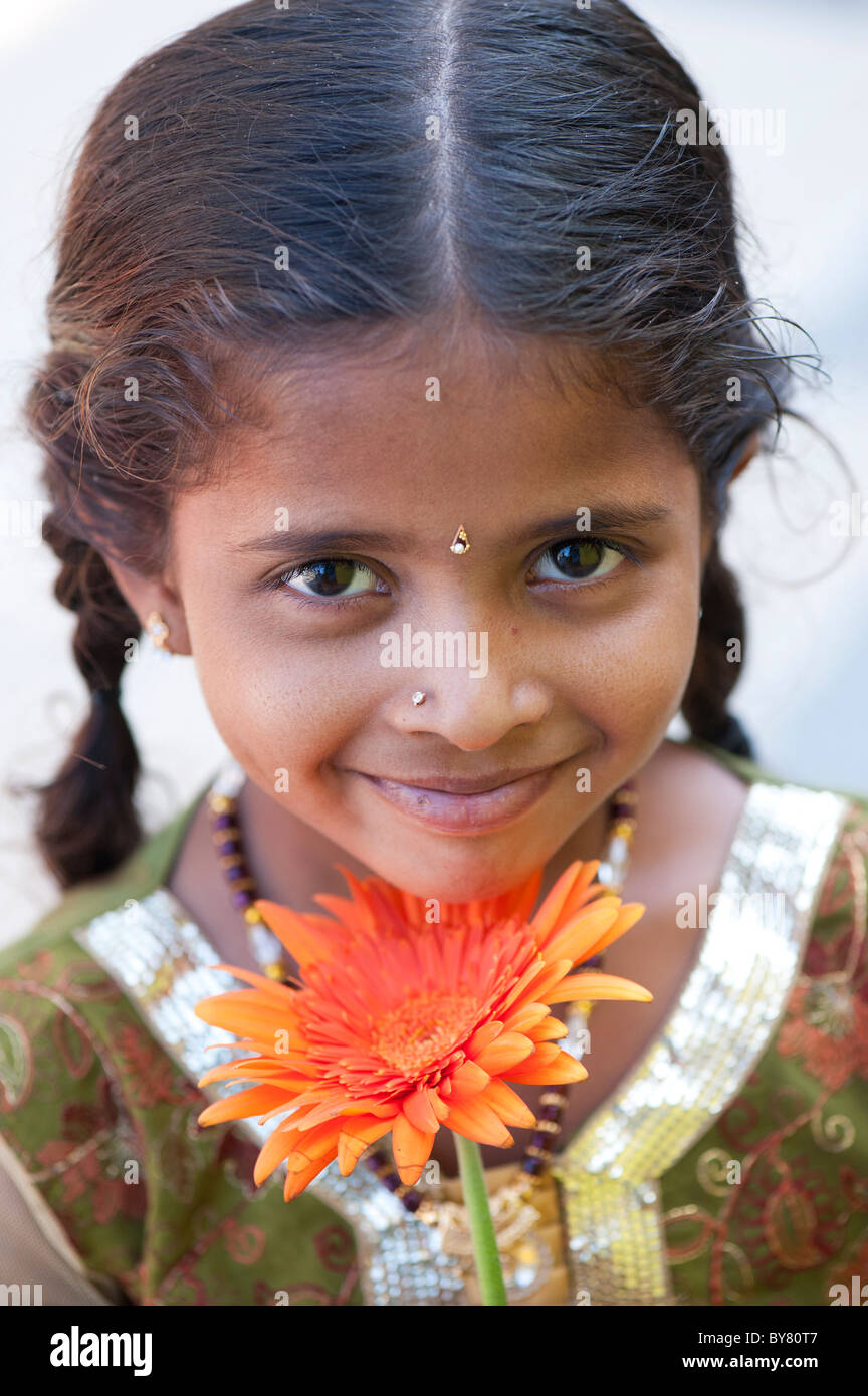 Smiling pretty young indian girl holding orange gerbera flower. Andhra Pradesh, India. Selective focus. Stock Photo