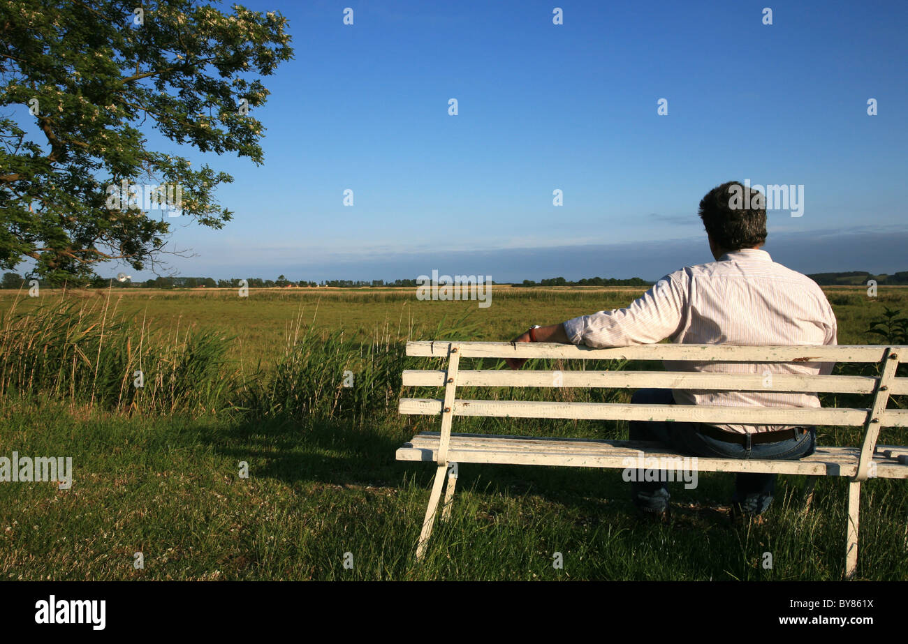 Man sitting on a park bench viewing the landscape Stock Photo - Alamy