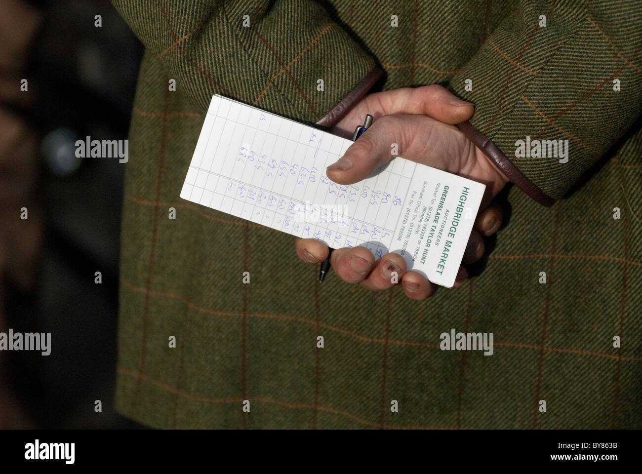 card of transactions and bids in farmers' hand behind back Stock Photo
