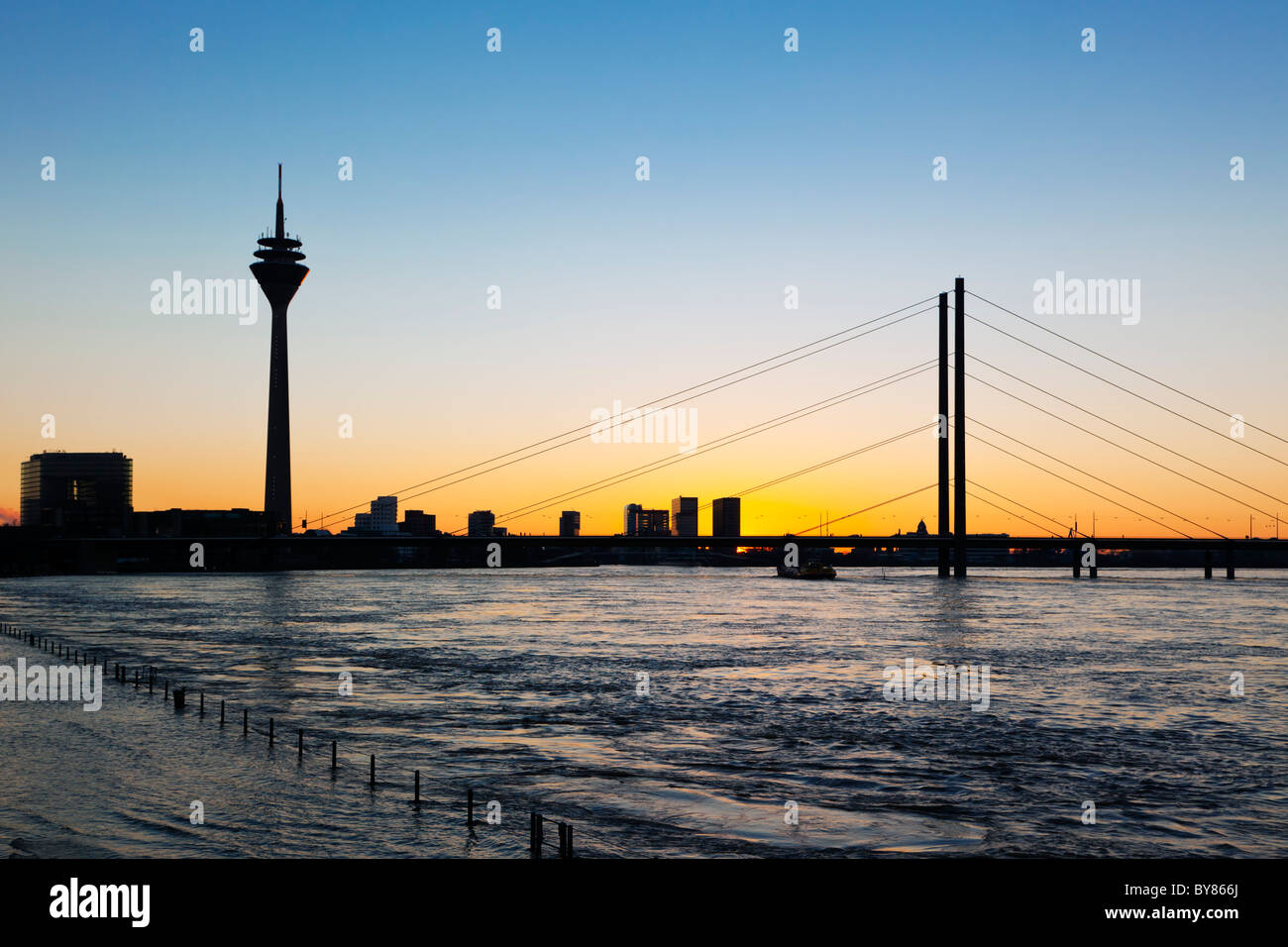 skyline of Dusseldorf with Rhine Tower, Rheinknie Bridge, MediaHarbor, silhouetted against sunset Stock Photo