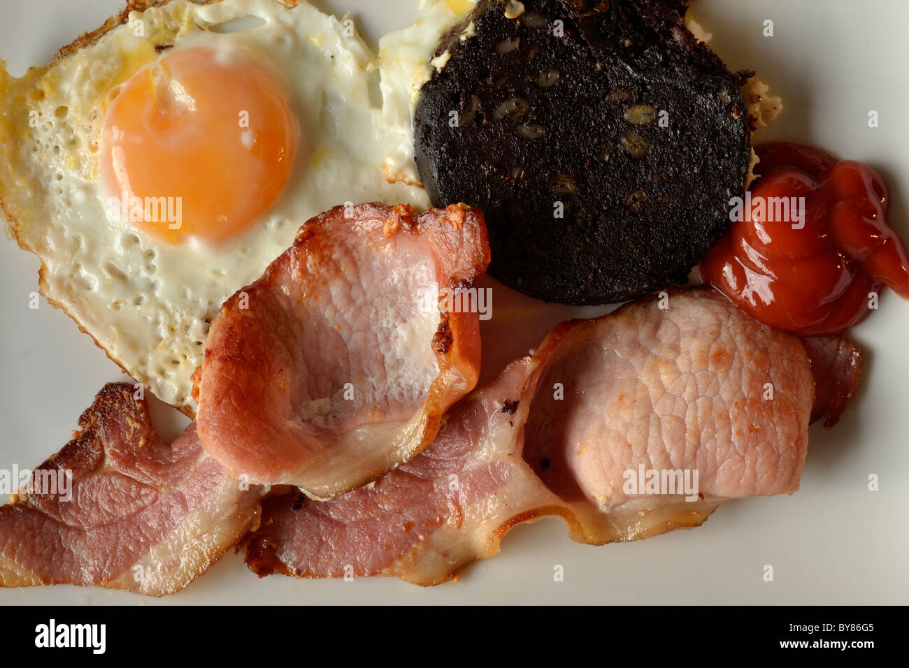 Fried breakfast of bacon, egg and black pudding with tomato sauce Stock Photo Alamy