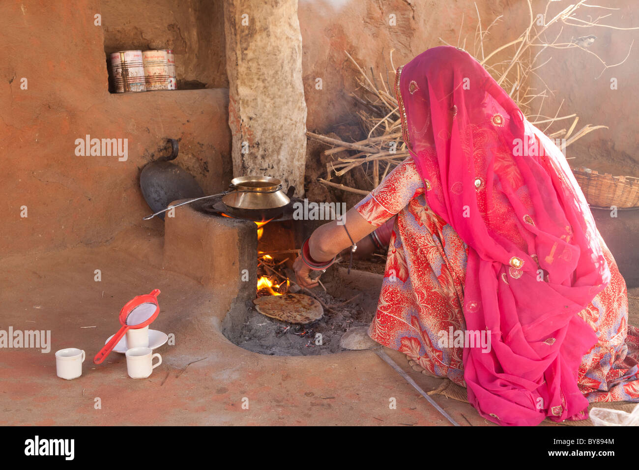 India, Rajasthan, Jodhpur, woman in traditional dress cooking roti (also known as chapati) on open fire Stock Photo