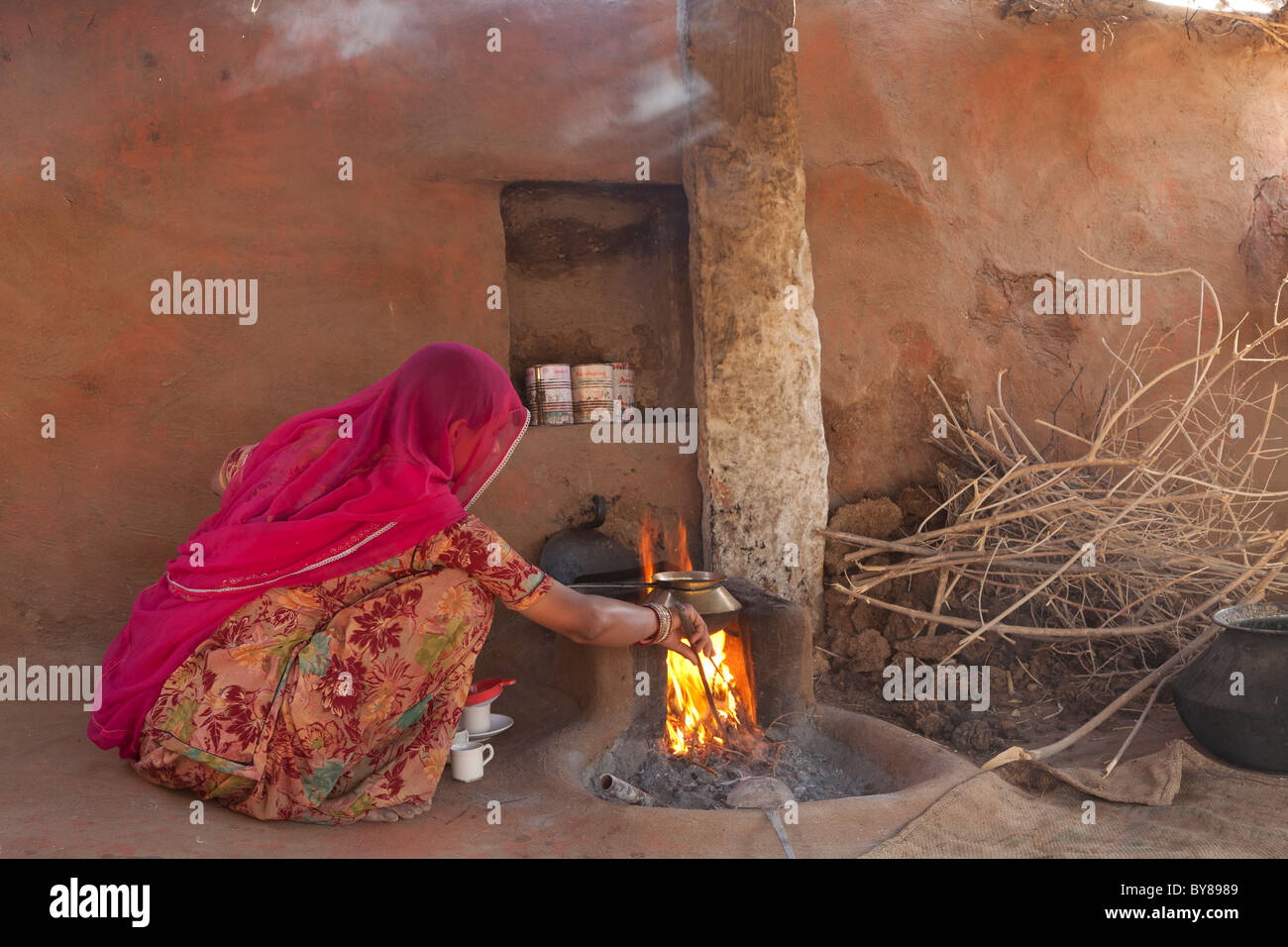 India, Rajasthan, Jodhpur, woman in traditional dress boiling water on open fire Stock Photo